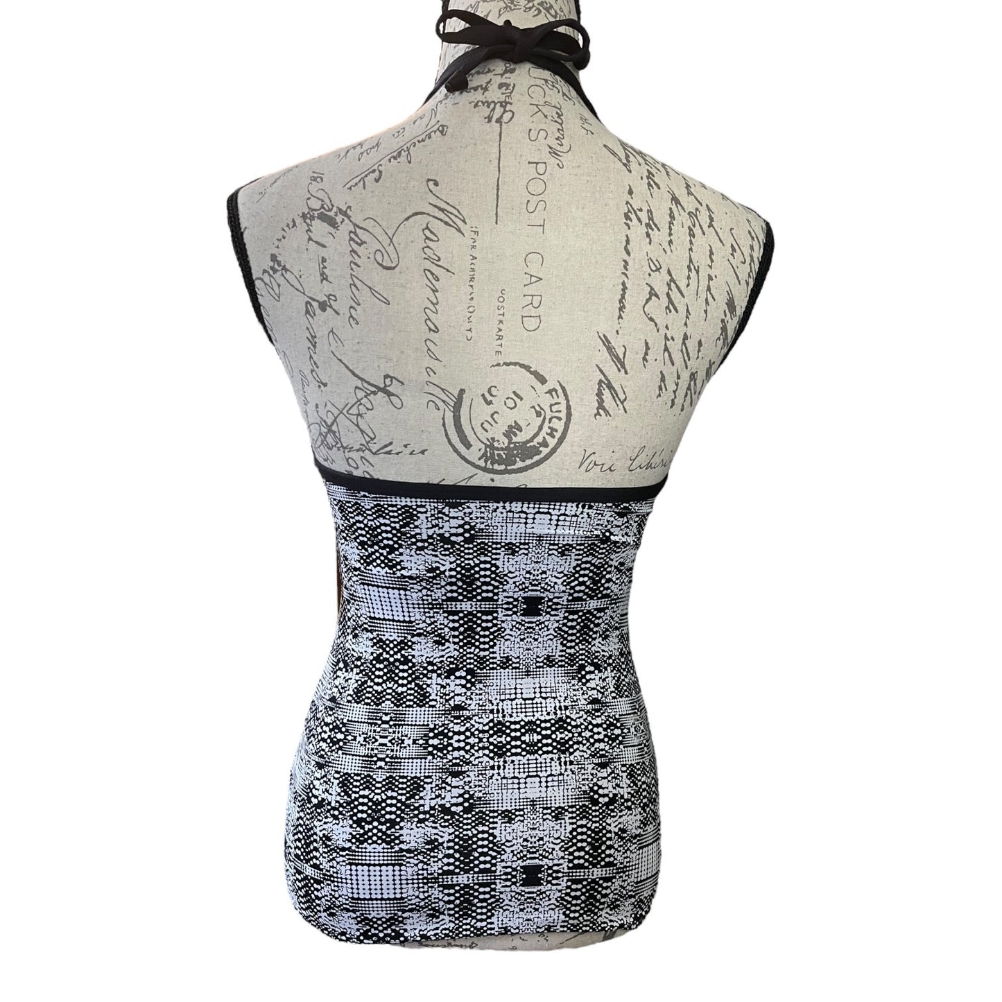 Back of black and white sleeveless swim top on a mannequin with vintage-style design on a white background