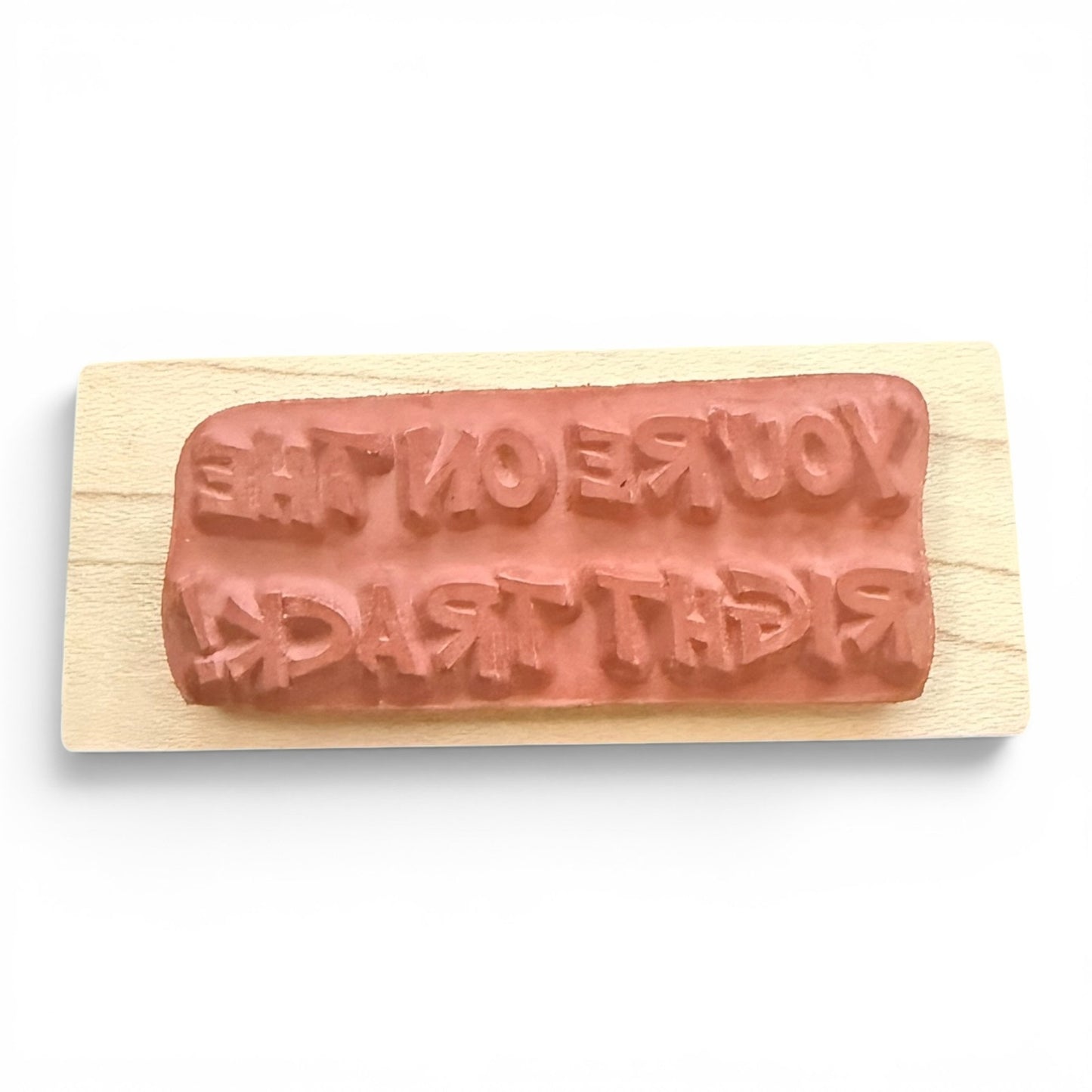 Rectangular wooden stamp with message embossed on a white background