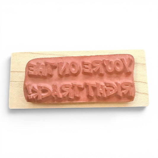 Rectangular wooden stamp with message embossed on a white background