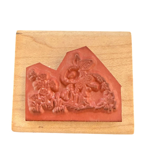 A stamp with a reddish-brown carved rubber mounted on a light-colored wooden block, shown against a plain white background.