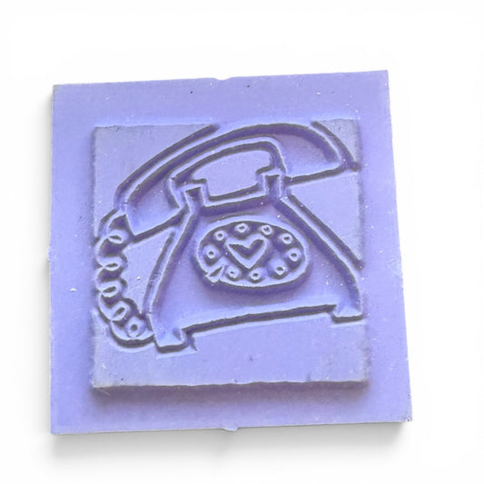 Lavender rubber stamp with a vintage telephone design on a white background