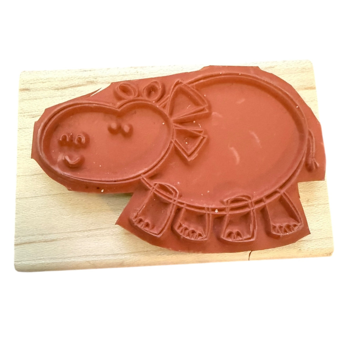 A hippo-shaped stamp , placed on a light wood block against a white background.