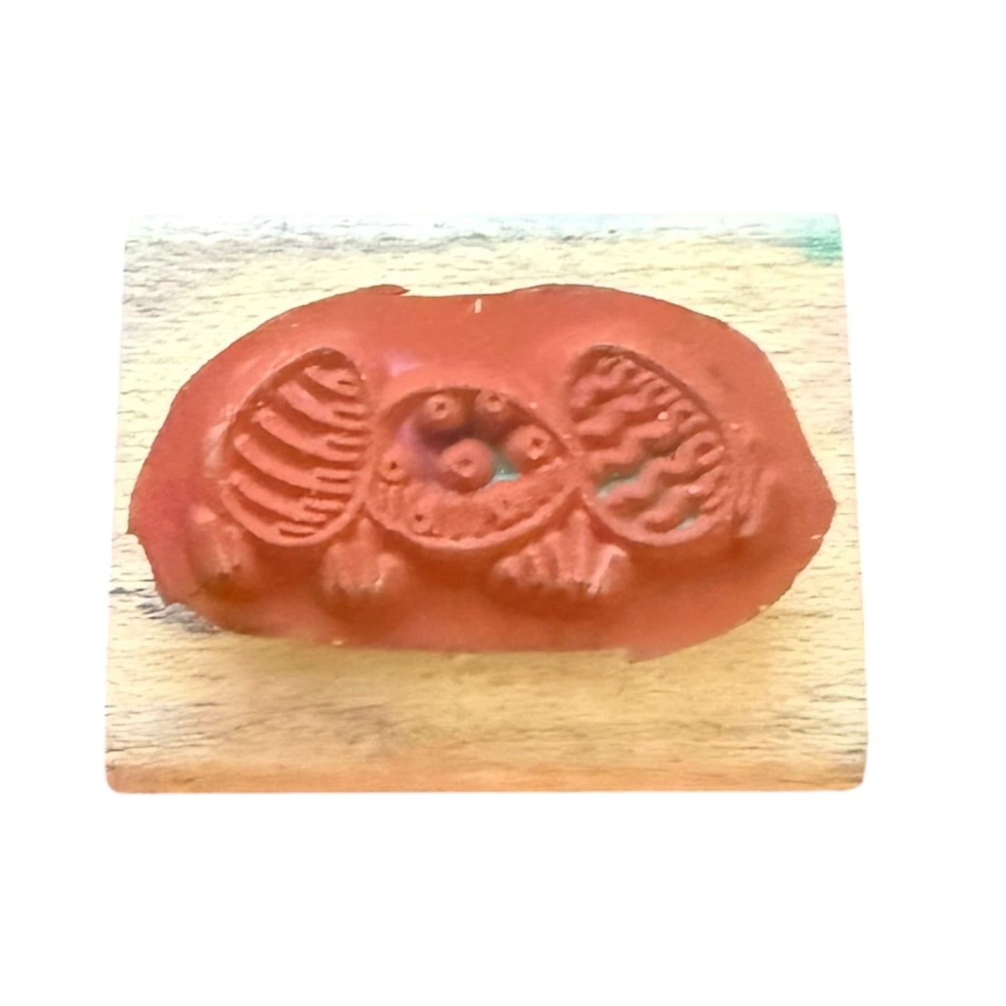 A terracotta-colored rubber stamp with a detailed Easter design, mounted on a light-colored wooden block against a white background.