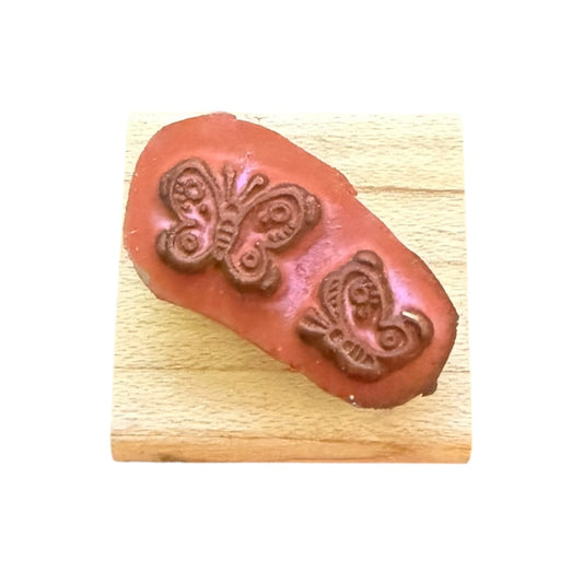 Butterfly-shaped stamp on a wooden block with a white background