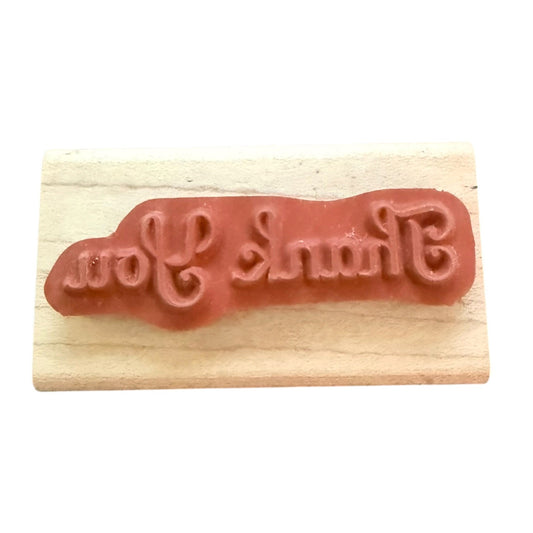 Thank You rubber stamp on a wood block with a white background.