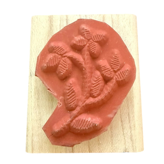 Red rubber stamp with leaf design on a wooden block