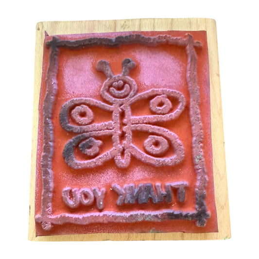 Decorative stamp with butterfly design and text on a wooden block