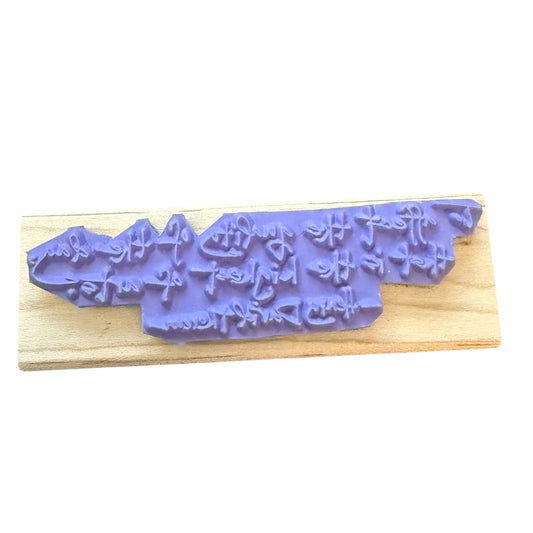 Purple rubber stamp with mountain design on a wooden board
