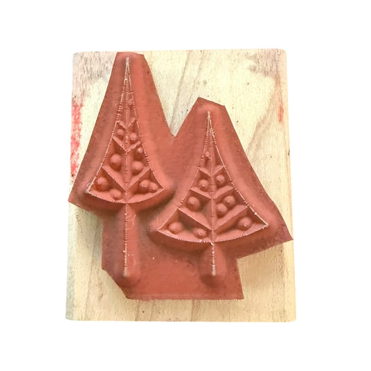 A wooden rubber stamp featuring two Christmas tree designs, shown with red ink on a light wood block against a white background.