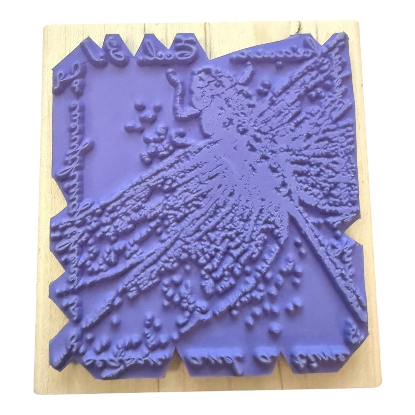 A purple rubber stamp with an embossed dragonfly design, mounted on a light-colored wooden block against a white background.