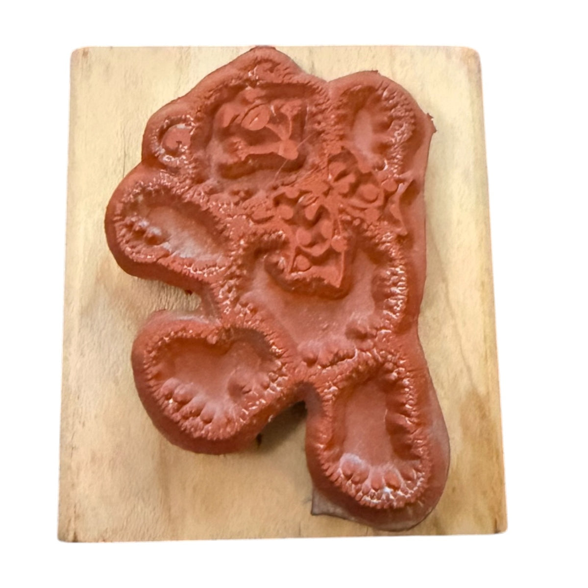 A terracotta-colored rubber stamp featuring a stylized bear design , mounted on a light-colored wooden block against a white background.