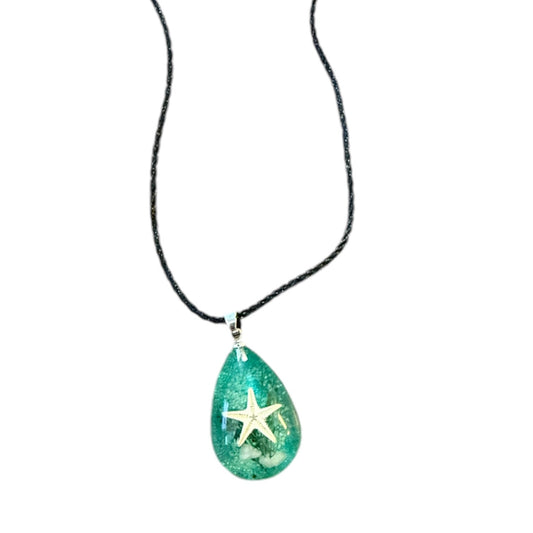 Teal pendant with a starfish on a black cord against a white background