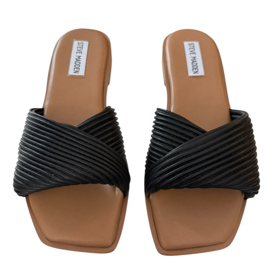 Black strappy sandals with brown soles on a white background