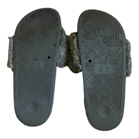 Bottom of a Pair of Gray slides with textured soles on a white background