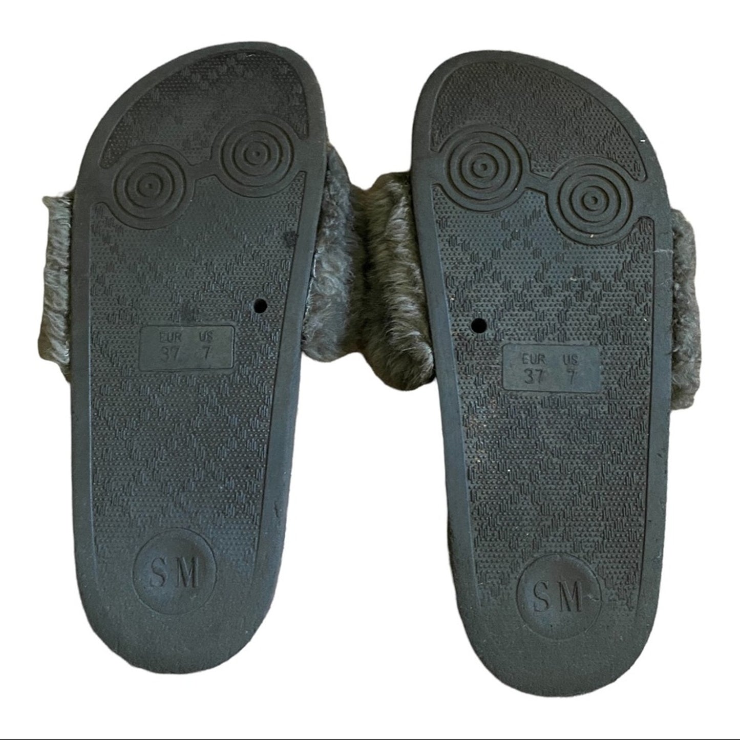 Bottom of a Pair of Gray slides with textured soles on a white background