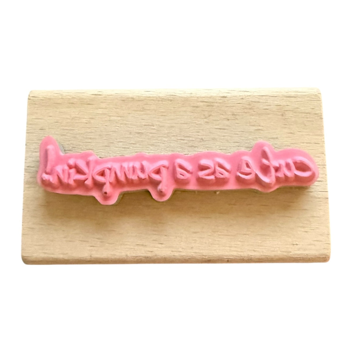 Pink lettering on a wooden block with white background