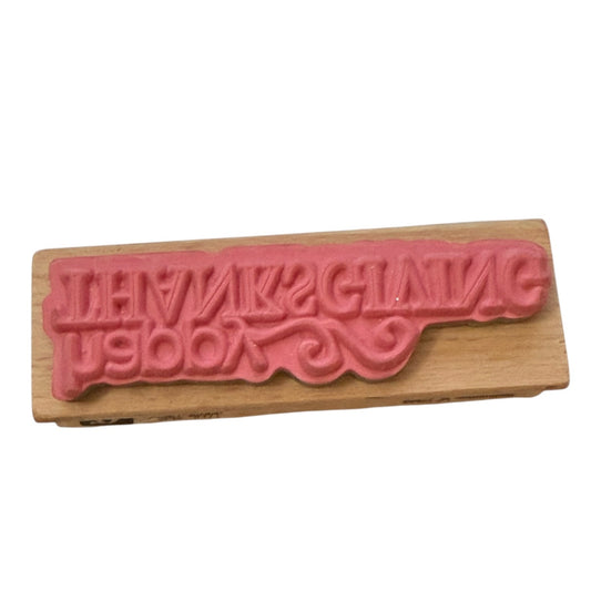 Wooden stamp with pink text on a white background