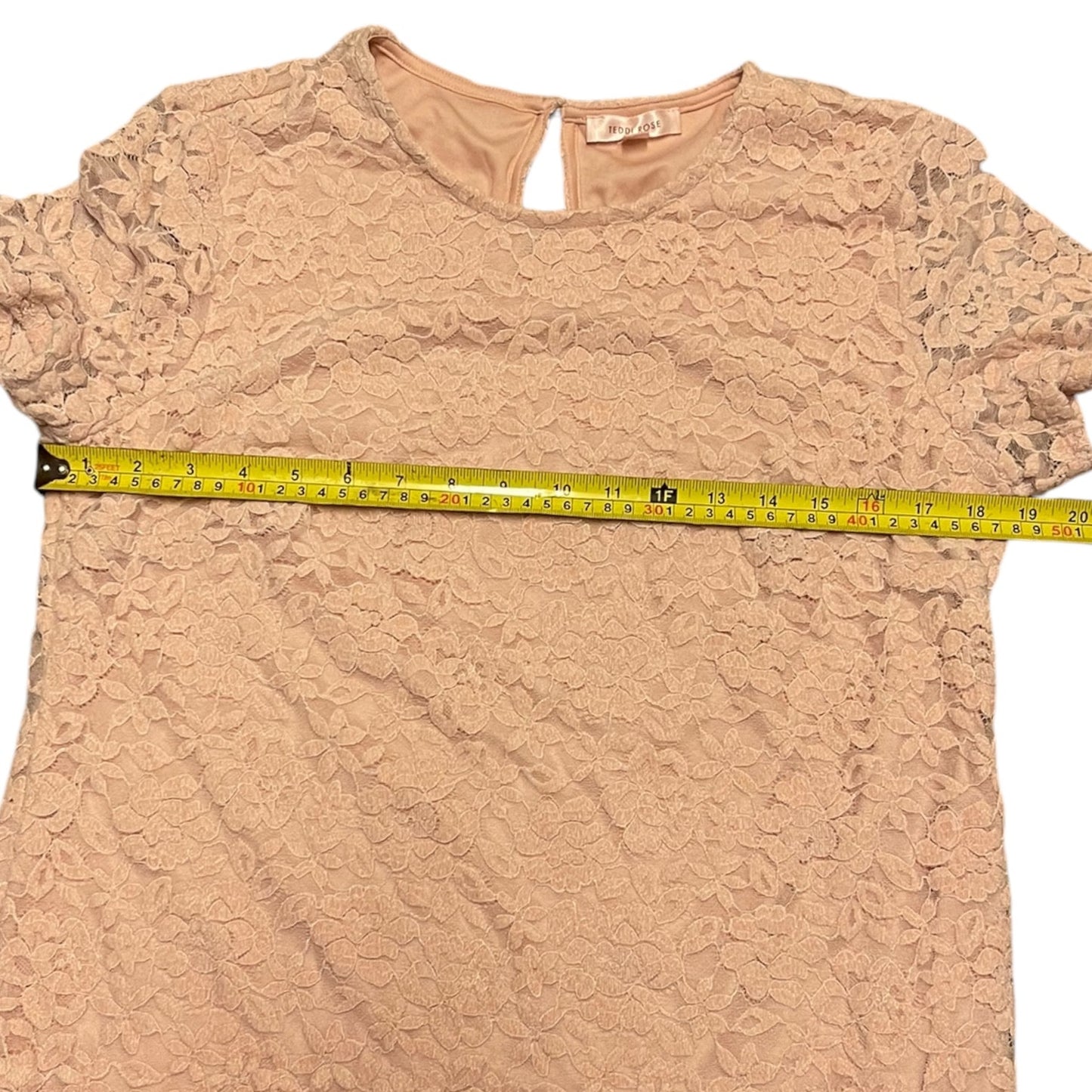 Pink lace top with a measuring tape on a white background