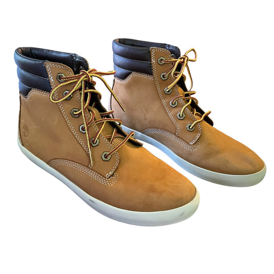 Pair of brown boots with white soles on a white background