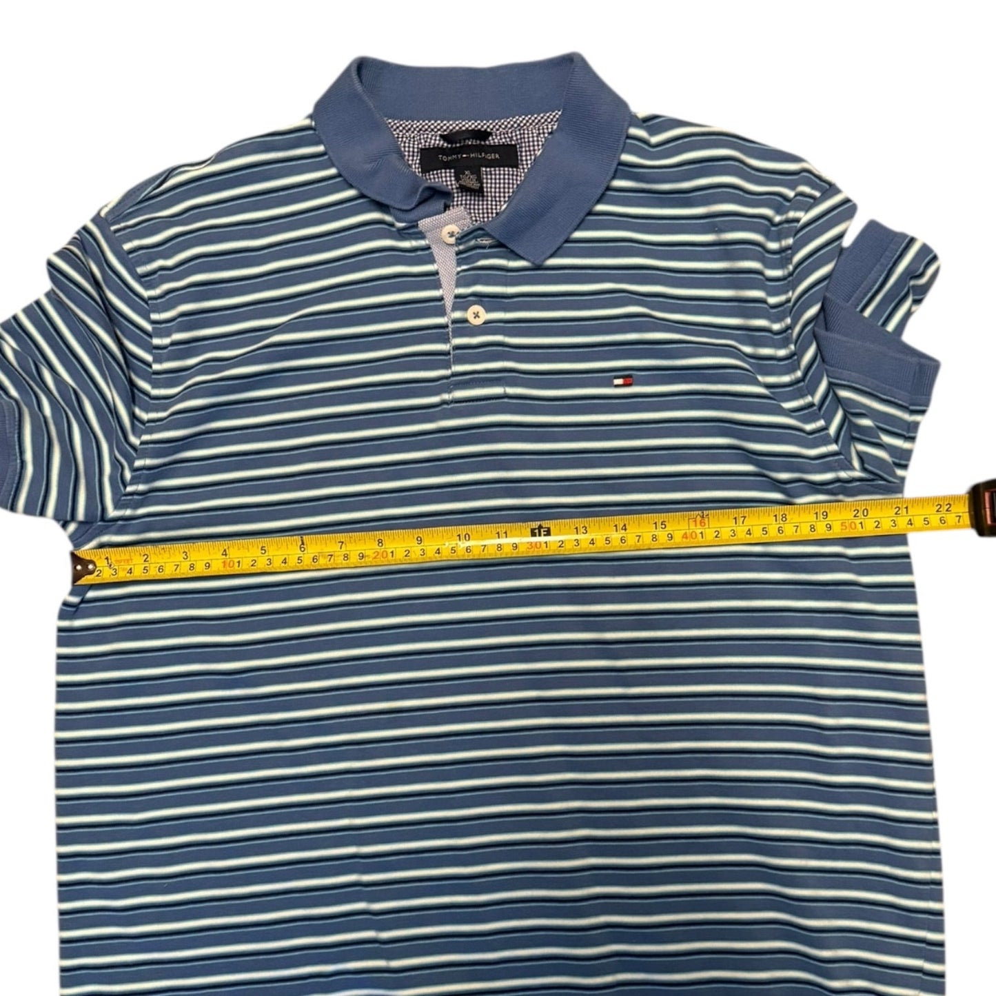 Blue and white striped polo shirt with a measuring tape on a white background