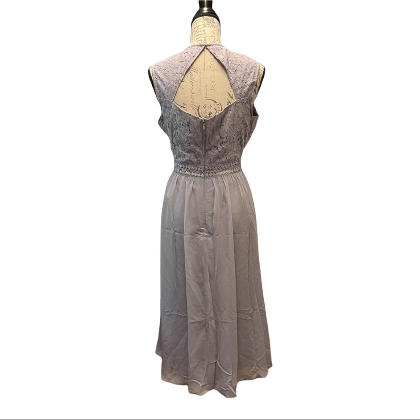 A sleeveless midi dress displayed on a dress form mannequin against a plain white background. The dress features a textured, patterned lavender with a keyhole cutout and a flowing, semi-sheer lavender skirt.