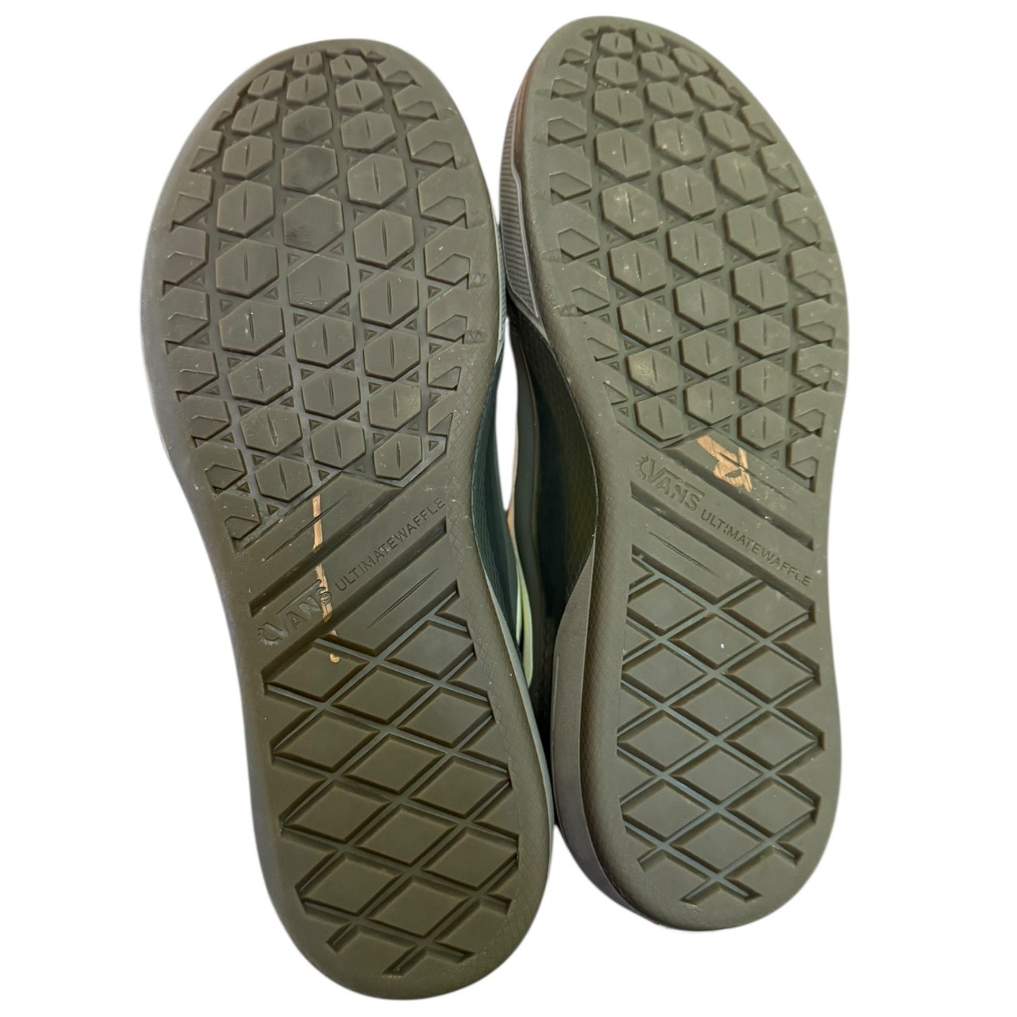 The soles of a pair of shoes shown from above, featuring a dark green textured tread pattern .