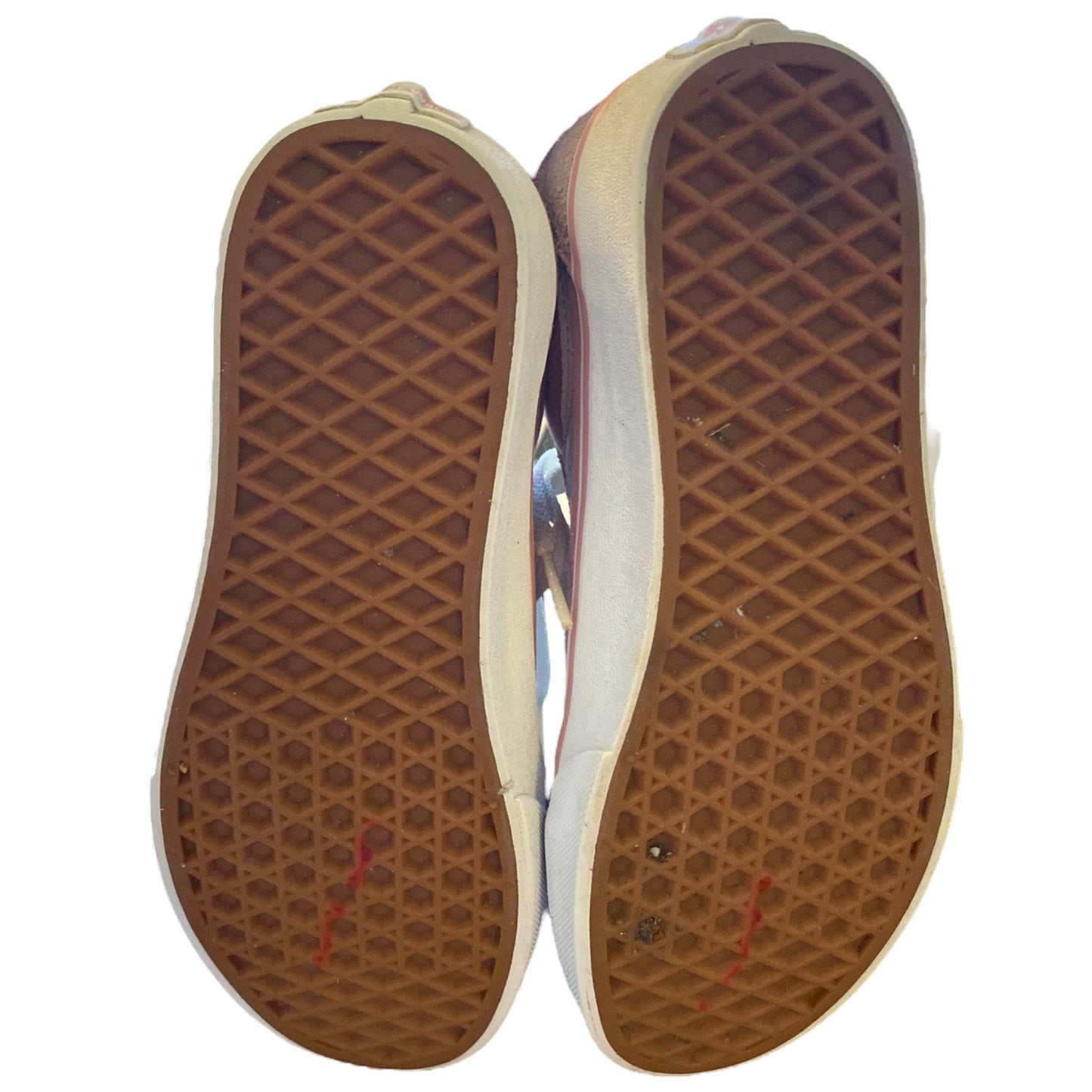 The outsoles of a pair of low-top sneakers, showing brown Vans-style waffle-patterned rubber with a white sidewall, photographed against a plain white background.
