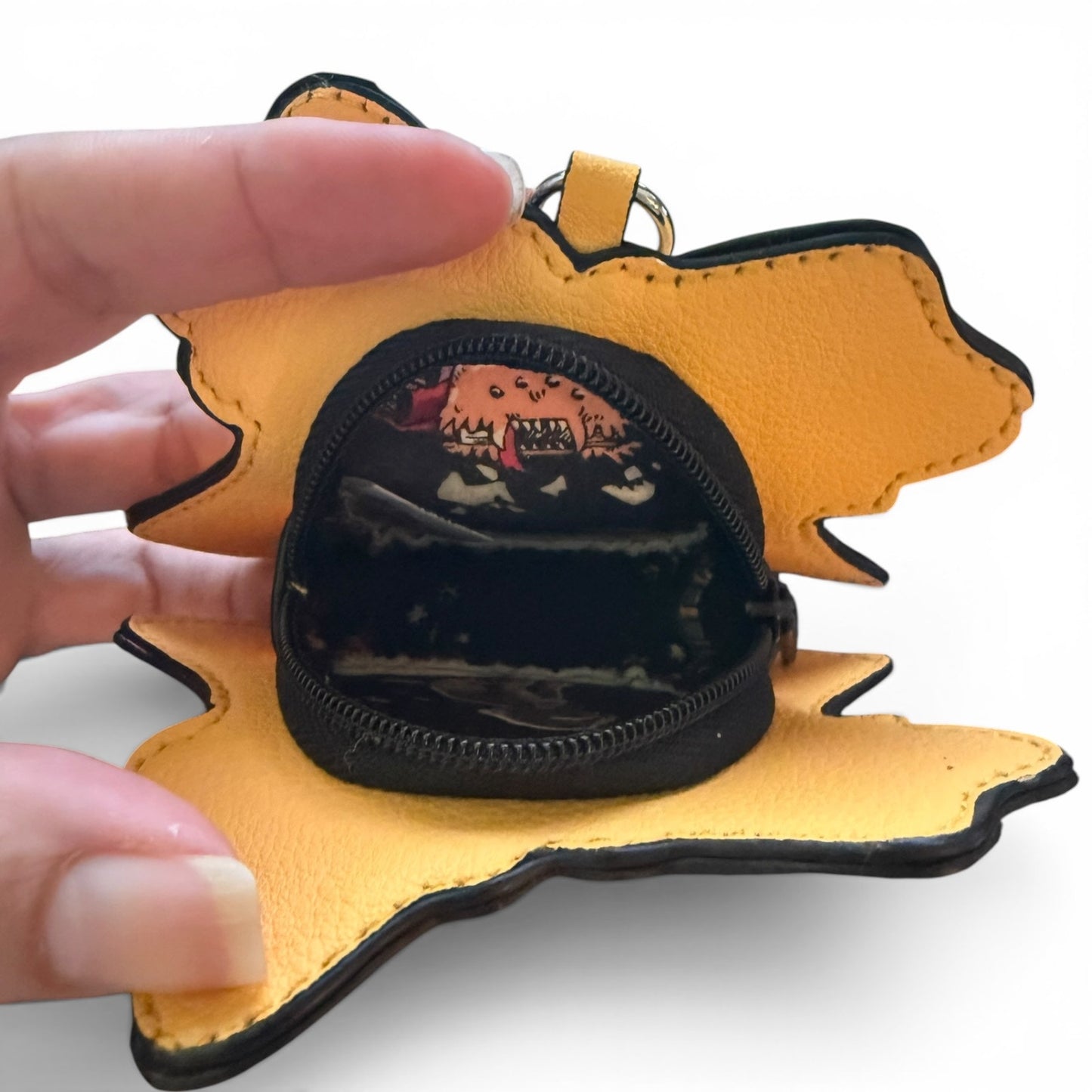Yellow pouch with a black interior, held open by a hand on a white background