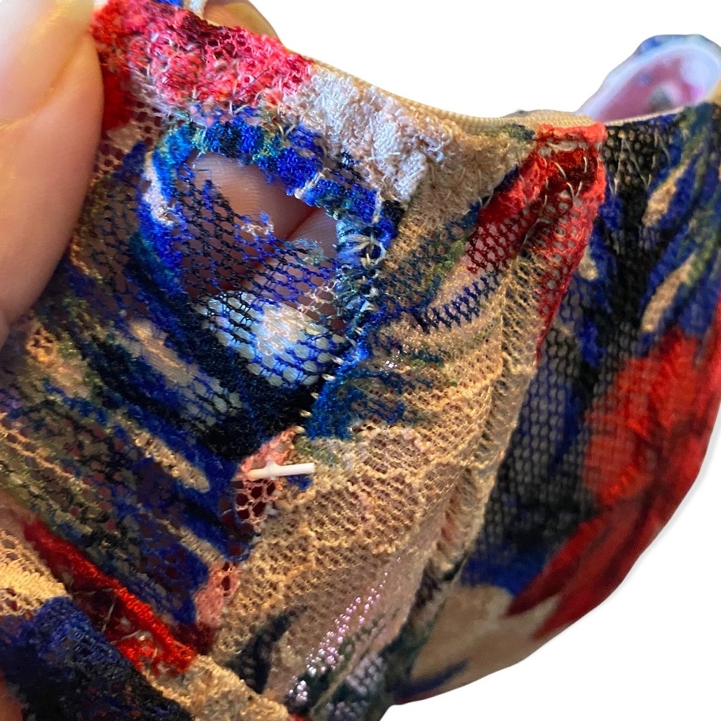 Close-up of a colorful textured fabric with a pattern and small hole.