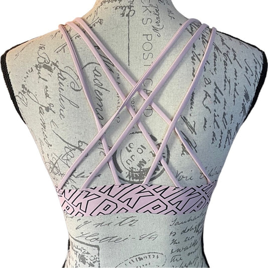Pink bra with PINK written on it with criss-cross straps on a white background