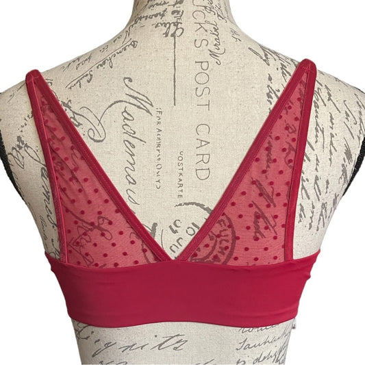 Red bra with a patterned design on a mannequin with a vintage-style background.
