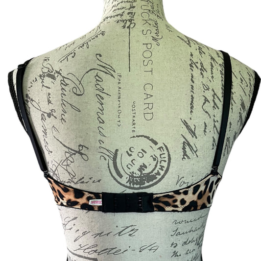 Mannequin wearing a bra with leopard print trim on a background of vintage lettering.