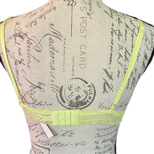 A bralette displayed on a vintage-style fabric mannequin torso. The bralette features thin shoulder straps, and a small white fabric tag.