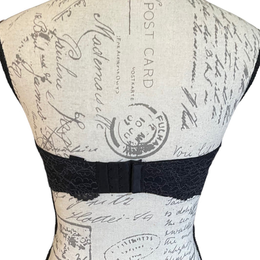 Back of Mannequin wearing a black lace bralette with a vintage-style printed design on the back.
