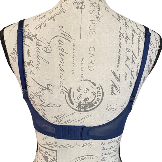 A navy blue bra with adjustable shoulder straps and a wide underband, displayed on a vintage-style patterned dress form mannequin against a white background.