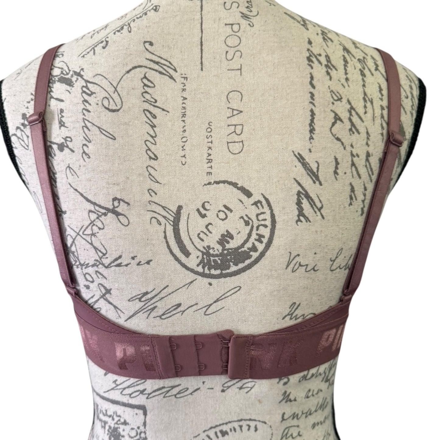 Back of purple bra with vintage-style text and stamp design on a beige background