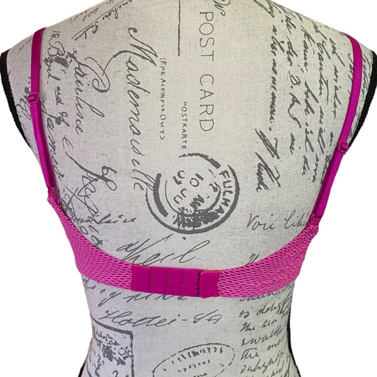 Mannequin wearing a bra with pink straps against a background of vintage-style text and stamps.