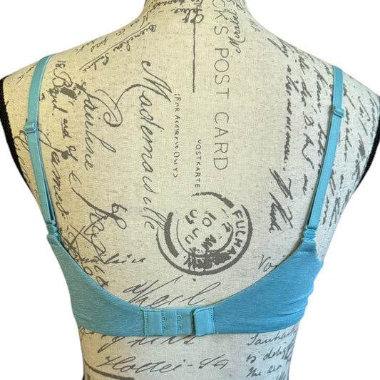 A light blue underwire bra displayed on a beige fabric-covered dress form mannequin, showing the back view of the bra with adjustable straps and a center back strap detail.
