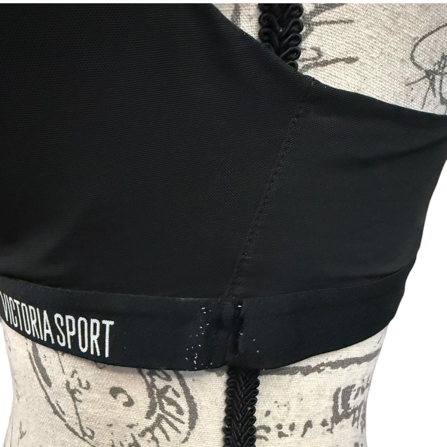 Black sports bra with 'Victoria Sport' label and showing issues on a patterned garment