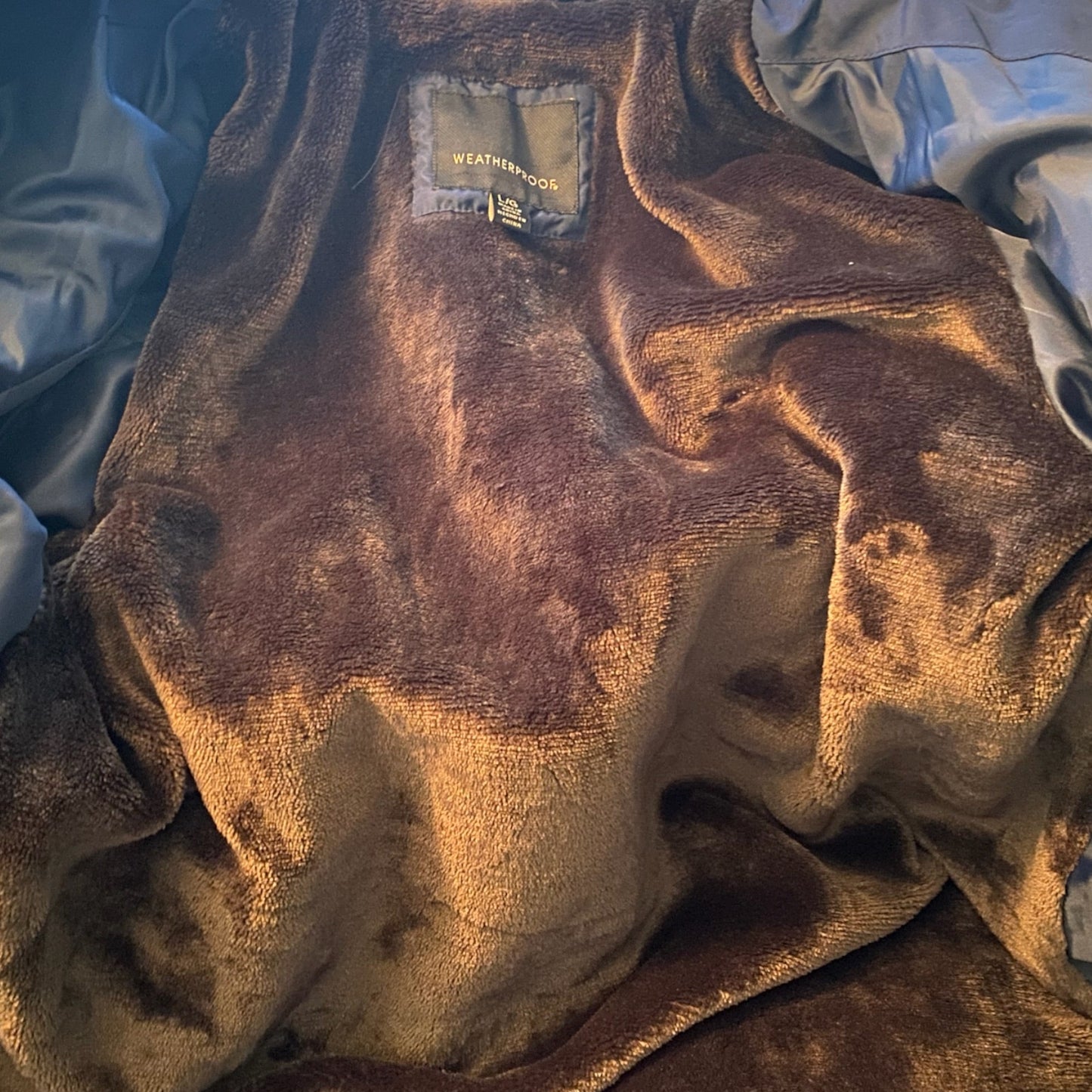 Interior of jacket with Brown textured fabric with a brand label on a blue and white background