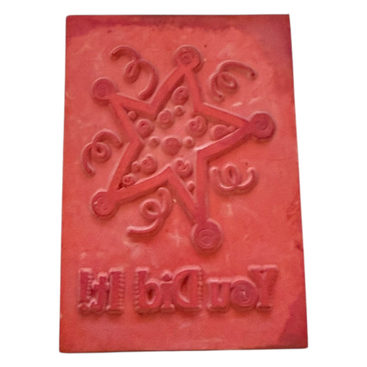Red rectangular block stamp with embossed design and text on a white background