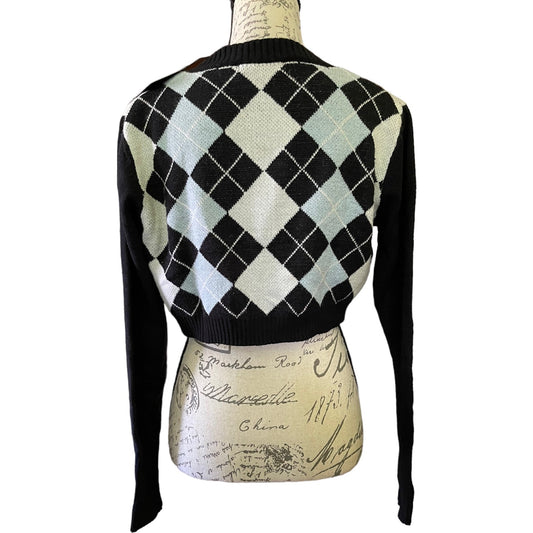 A cropped knit cardigan sweater shown from the back on a mannequin torso. The cardigan features a black and cream argyle pattern with light blue-gray diamonds and solid black sleeves and ribbed collar.