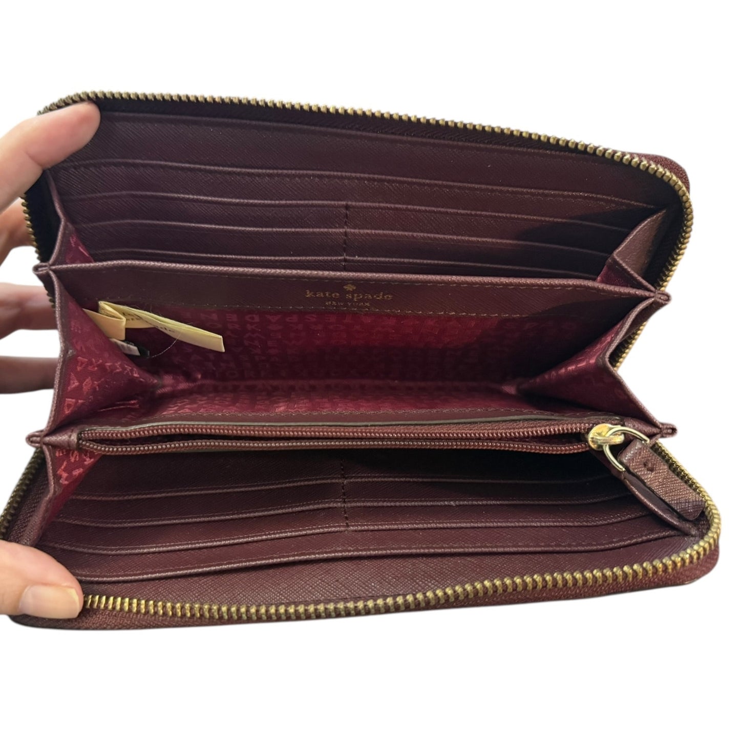 Interior wallet with gold zipper held open by a hand on a white background