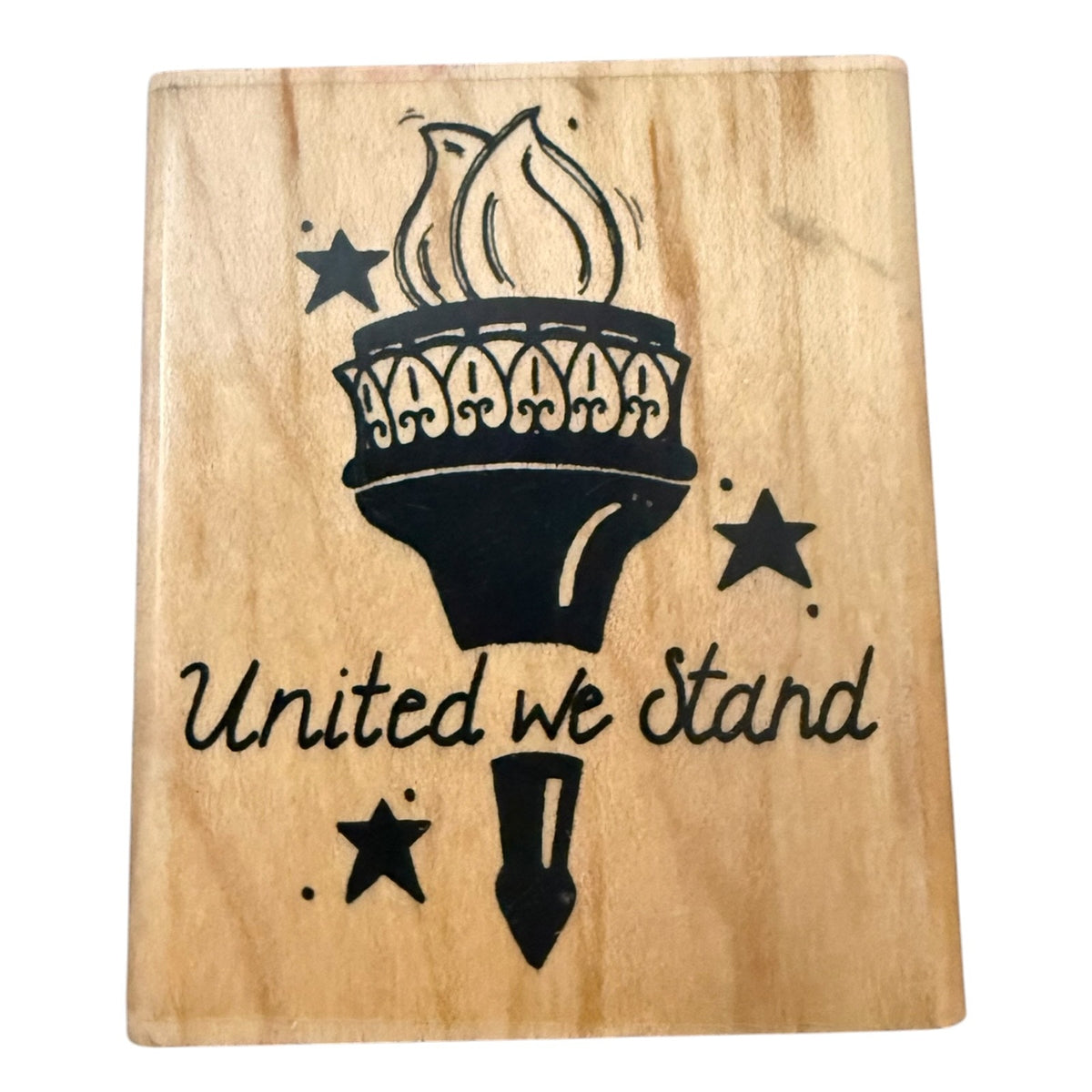 A square wood block stamp with a natural light wood grain finish, featuring a black  graphic of a torch, stars, and the text 'United we stand'.
