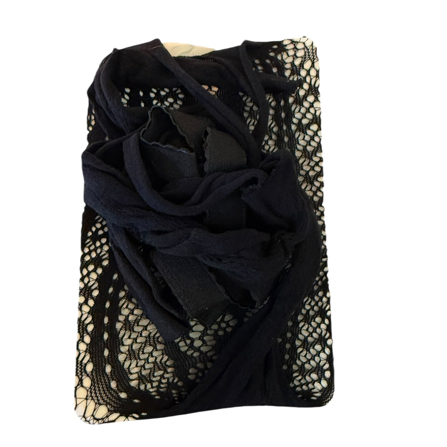 A folded black sheer lace and mesh Lingerie draped over a cream-colored rectangular garment or fabric piece, shown on a plain white background.