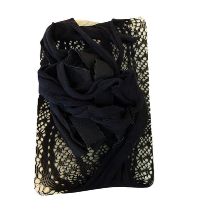 A folded black sheer lace and mesh Lingerie draped over a cream-colored rectangular garment or fabric piece, shown on a plain white background.