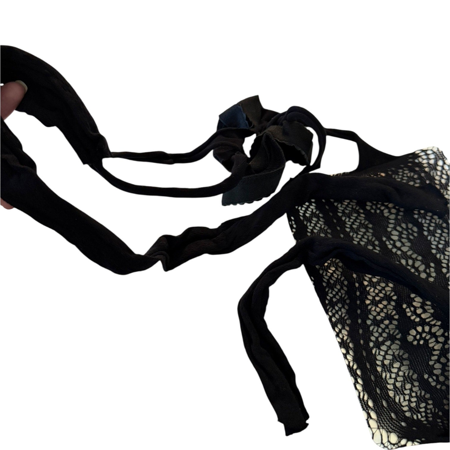 A black lace and mesh lingerie, shown against a plain white background with a hand holding one strap on the left.