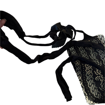 A black lace and mesh lingerie, shown against a plain white background with a hand holding one strap on the left.