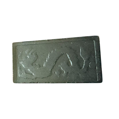 Rectangular black domino with embossed design on a white background