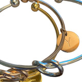 Close-up of a gold and silver bracelet with a 'Y' charm on a white background